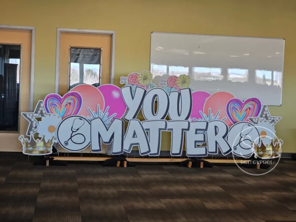 A large sign in a room that says "YOU MATTER" in white letters. Colorful graphics of surround the sign.