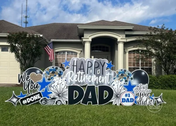 A yard sign in front of house that says "Happy Retirement Dad" in Black and White letters. Colorful graphics surround the sign.