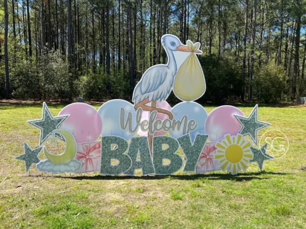 A yard sign that says "Welcome BABY" in silver letters. A graphic of a large stork with a yellow sack in its beak stands behind the phrase with colorful graphics of balloons and stars surround the sign.