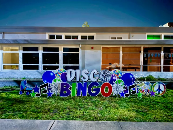 A yard sign in front of building that says "DISCO BINGO" in various letters. Colorful graphics surround the sign.