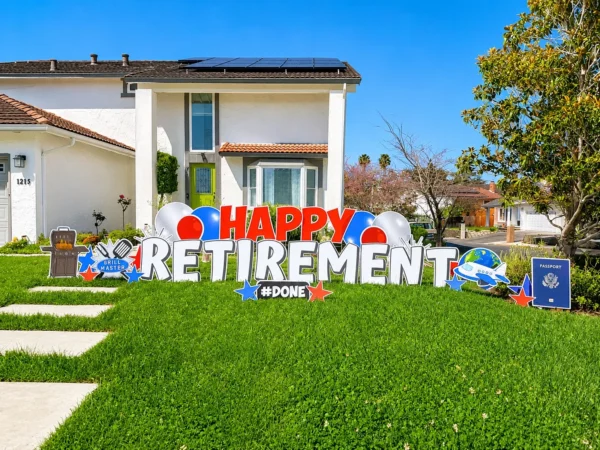 A yard sign in front of house that says "HAPPY RETIREMENT" in red and white letters. Colorful graphics surround the sign.