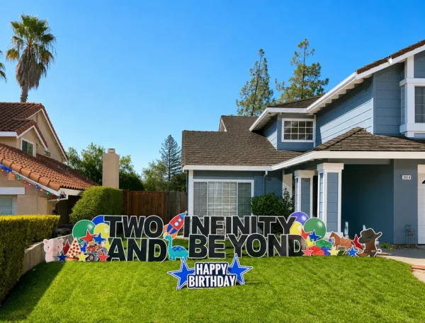A yard sign in front of a house that says "TWO INFINITY AND BEYOND HAPPY BIRTHDAY" in black and white letters. Colorful graphics surround the sign.