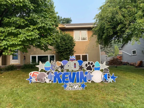 A yard sign in front of a house that says "40 Kevin Happy Birthday". The phrase is surrounded by colorful graphics.