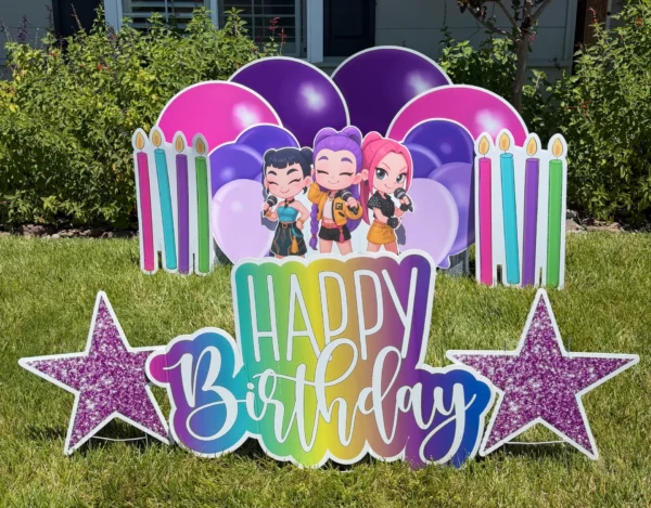 A yard sign in front of a house that says "Happy Birthday" with three cartoon characters standing behind the phrase. The phrase is surrounded by colorful graphics.