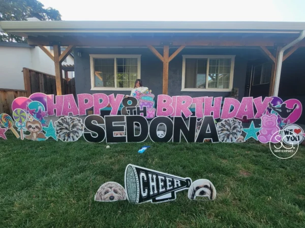 A yard sign that says "HAPPY 8th BIRTHDAY SEDONA" in pink and black letters with colorful graphics surrounding it and a girl standing behind the sign.